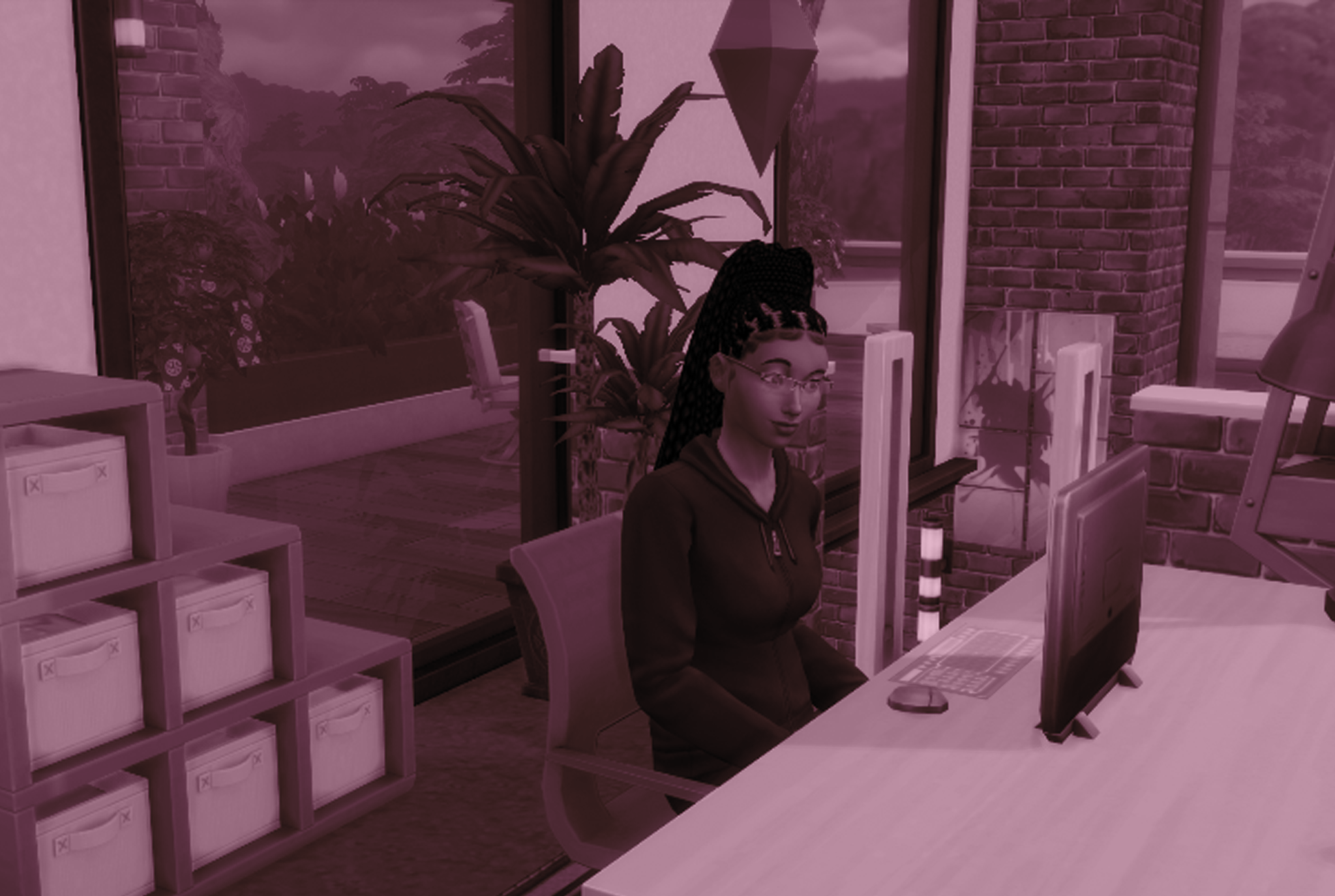 A Sims character, a Black woman with long hair, sits at a desk in front of a computer.